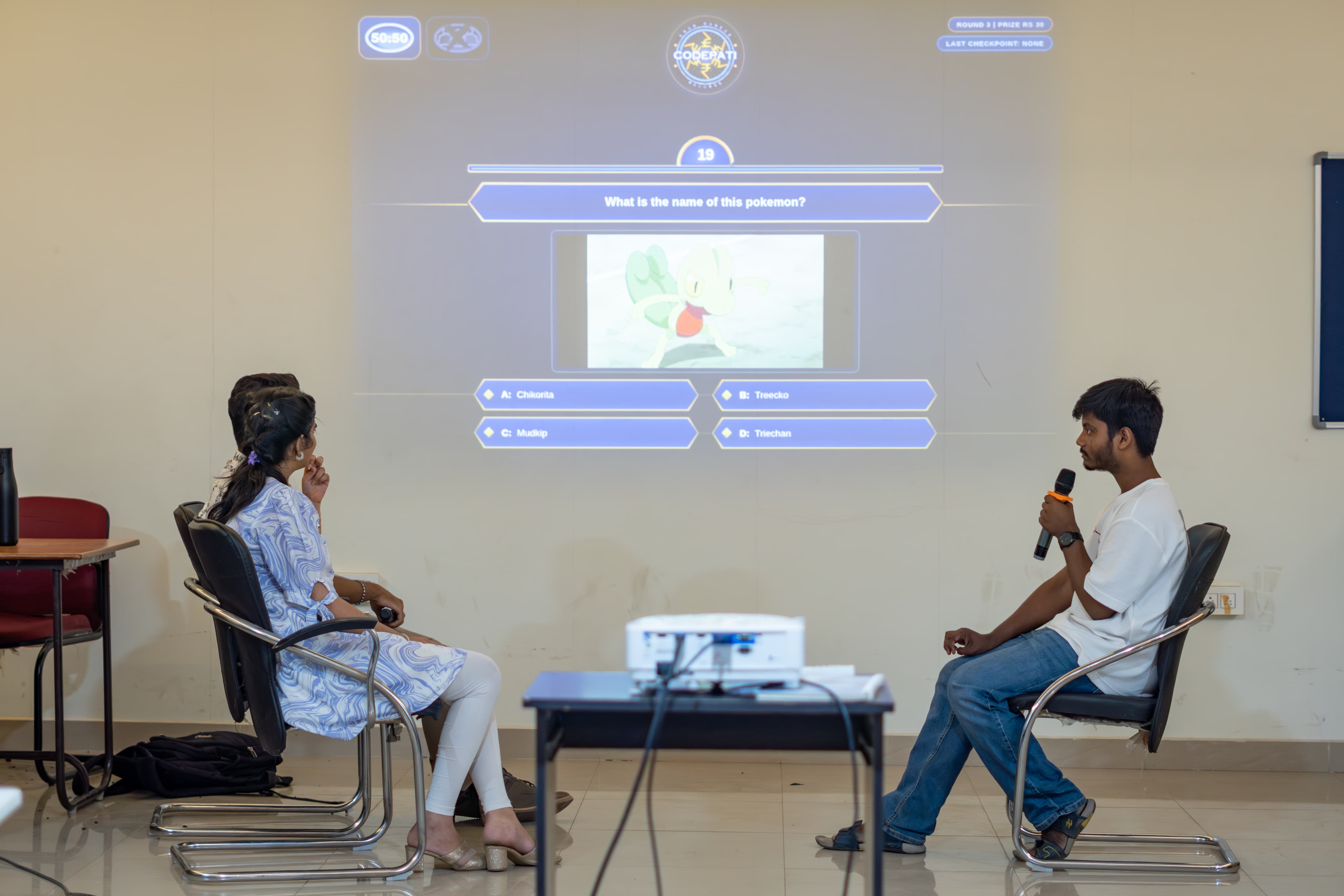 KBC contestants seated in front of the projected quiz screen
